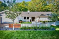 a white house sitting on top of a lush green field next to a tree and grass covered yard