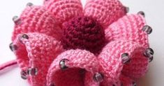 a crocheted pink flower with black dots on it sitting on a white surface