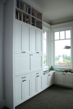 an empty room with white cabinets and bookshelves next to a window in the corner