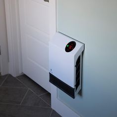 a white wall mounted heater sitting next to a door on top of a tiled floor