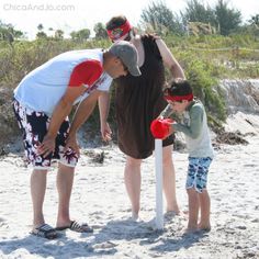 a man and two children playing baseball on the beach