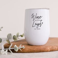 a white wine glass sitting on top of a wooden cutting board next to some leaves