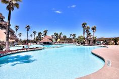 an outdoor swimming pool with palm trees and blue sky in the background at a resort