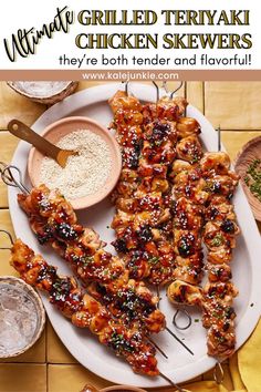 grilled teriyaki chicken skewers on a white plate with dipping sauce