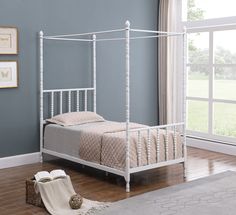 a white metal bed frame in a room with hardwood floors and blue walls, along with a rug on the floor