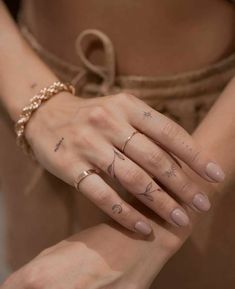 a woman's hand with three different tattoos on her left wrist and two fingers