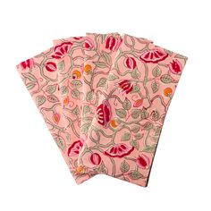 three pink napkins with red and green designs on them