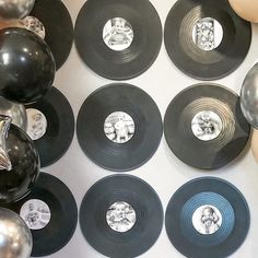 there are many black and silver records on the wall with balloons in front of them