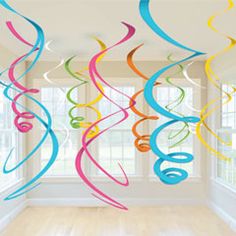 multicolored streamers hanging from the ceiling in an empty room with white walls