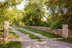 a stone wall and walkway between two trees