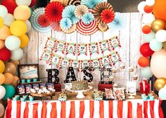 an american flag themed dessert table with balloons and paper fan garlands on the wall