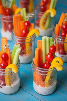 small mason jars filled with veggie cups on top of a blue tablecloth