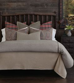 a bed with pillows and blankets on top of it next to a wooden headboard