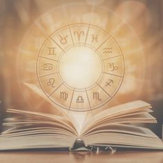 an open book sitting on top of a table next to a pen and magic wheel