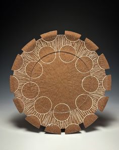 a wooden plate with circles and lines on it's surface, in the shape of a sunburst