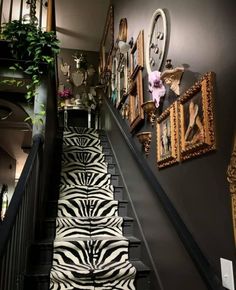 the stairs are decorated with zebra prints and framed pictures on the wall, along with plants