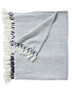 a gray and white blanket with fringes on it