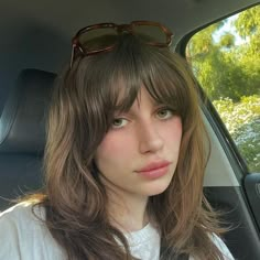 a woman with sunglasses sitting in the back seat of a car looking at the camera