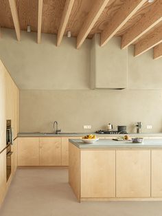 an empty kitchen with wooden ceiling and white counter tops, along with wood paneling on the walls