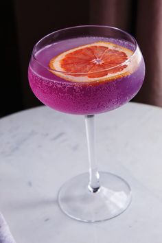 a purple drink with an orange slice on the rim