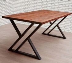 a wooden table sitting on top of a hard wood floor next to a brick wall