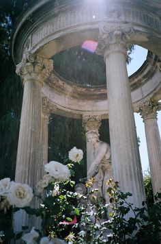 the sun shines brightly on an old gazebo with white flowers in front of it