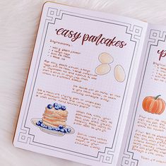 an open recipe book with pictures of pancakes and pumpkins on the pages, sitting on top of a white furnishing