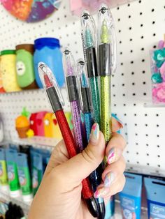 a person holding several pens in their hand and some other items on the wall behind them