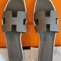 Hermes Oran Sandal Etain Gray Epsom Leather Limited Summer 2022 Size 40/ 10us Insole Measures 10.45inch Comes W Hermes Box, 2 Dust Bags. Sandal In Epsom Leather With Iconic "H" Cut-Out. An Iconic Hermes Style Natural Leather Sole Leather Heel Insole And Lining Made In Italy. Condition: Fainted Scratches On Outsole. Hermes Heels, Luxury Sandals, Hermes Style, Push Presents, Hermes Shoes, Hermes Oran, Hermes Box, Summer 2022, Natural Leather