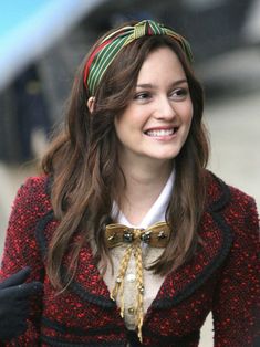 a woman with long hair wearing a red and black jacket, smiling at the camera