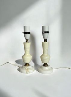 two white candlesticks sitting on top of each other next to a light bulb