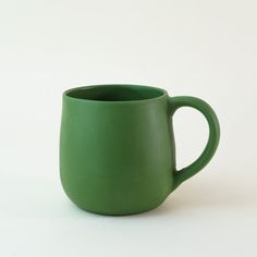 a green mug sitting on top of a white table