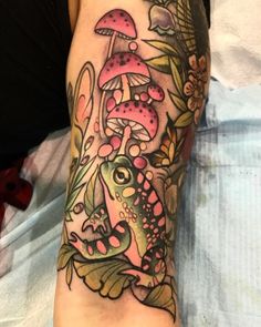 a person with a tattoo on their arm has a frog and mushrooms in the background