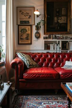 a red leather couch in a living room with pictures on the wall and rugs