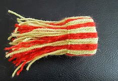 a red, white and yellow striped piece of cloth on a black surface with some thread