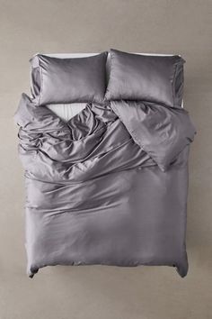 an unmade bed with two pillows and a comforter on top of the bed