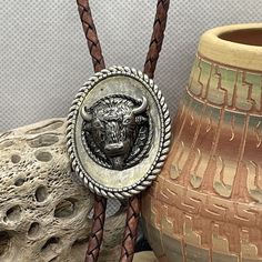 a bull head on a leather necklace next to a vase