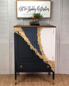 a black and white cabinet with gold paint on the top, next to a sign that says not to sulfy restoration