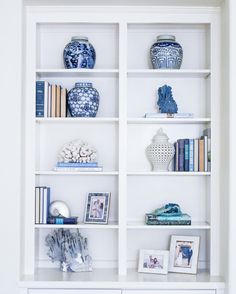 a white bookcase filled with blue and white vases