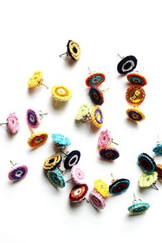 small crocheted earrings are arranged on a white surface