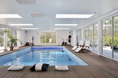 an indoor swimming pool with sunroofers and lounge chairs