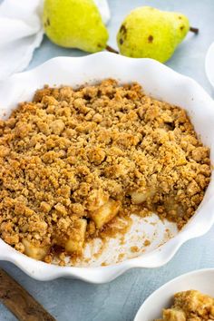 a close up of a pie in a bowl on a table with two pears