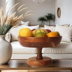 a wooden bowl filled with fruit sitting on top of a table next to a white couch