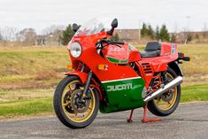 a red and green motorcycle parked on the side of a road next to a field