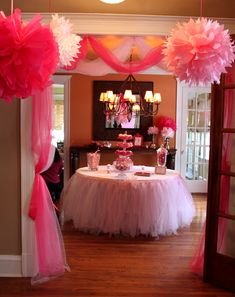 a table with pink and white decorations in the middle of a hall way at a birthday party