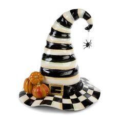 a black and white striped witch hat with pumpkins on the ground next to it