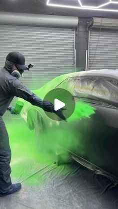 a man painting a car with green paint