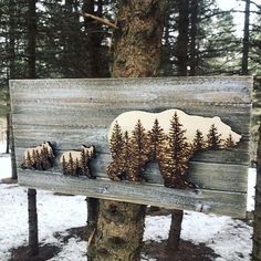 a wooden sign with three bears on it in front of snow covered ground and trees