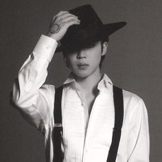 a young man wearing suspenders and a hat