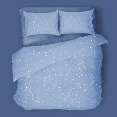 a bed with blue sheets and white stars on the comforter, along with two pillows